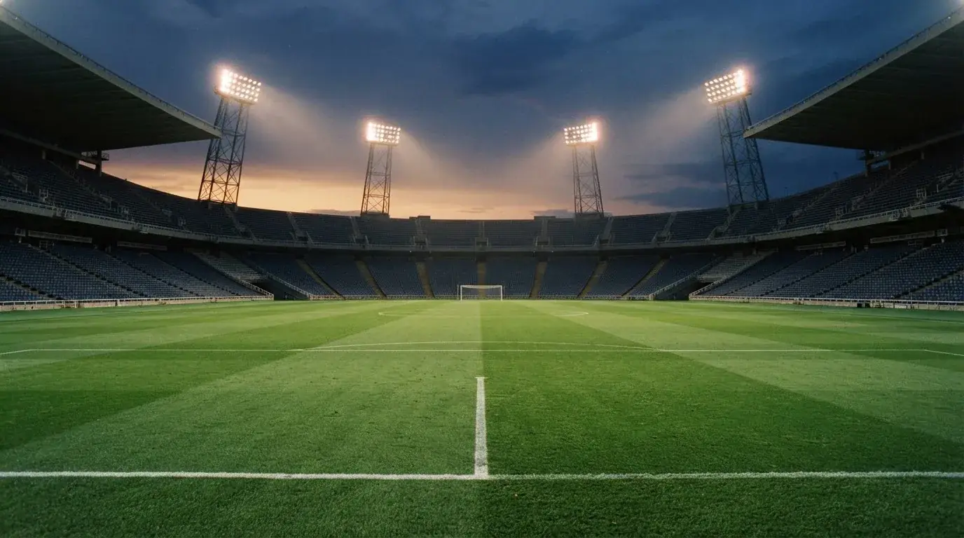 Een leeg voetbalstadion met lichtmasten bij schemering