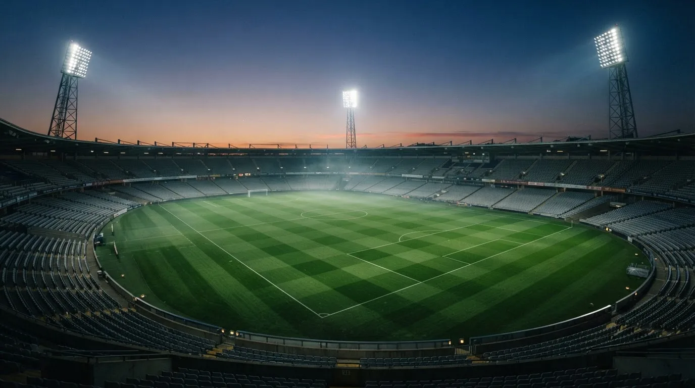 Een leeg voetbalstadion met lichtmasten bij schemering