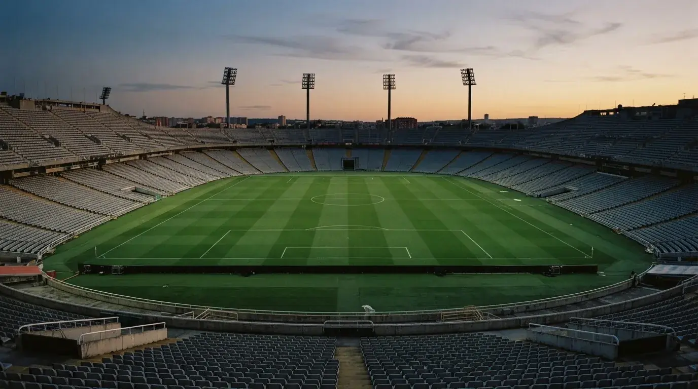 Een leeg voetbalstadion met lichtmasten bij schemering