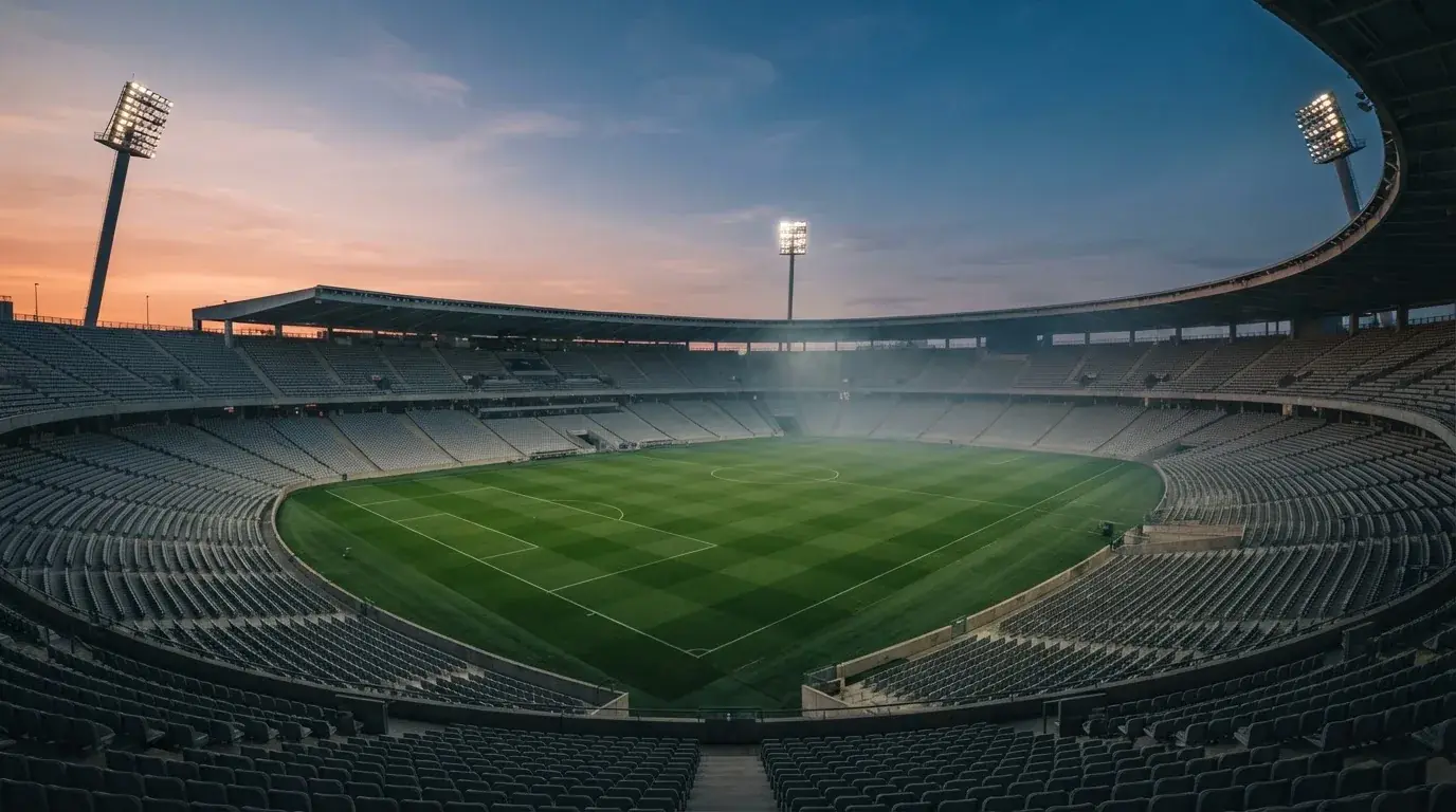 Een leeg voetbalstadion met lichtmasten bij schemering