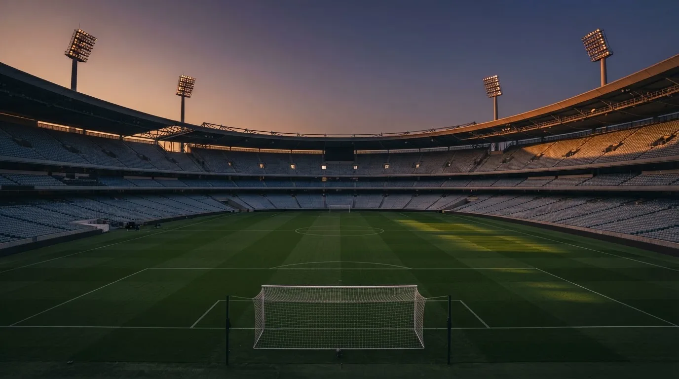 Een leeg voetbalstadion met lichtmasten bij schemering