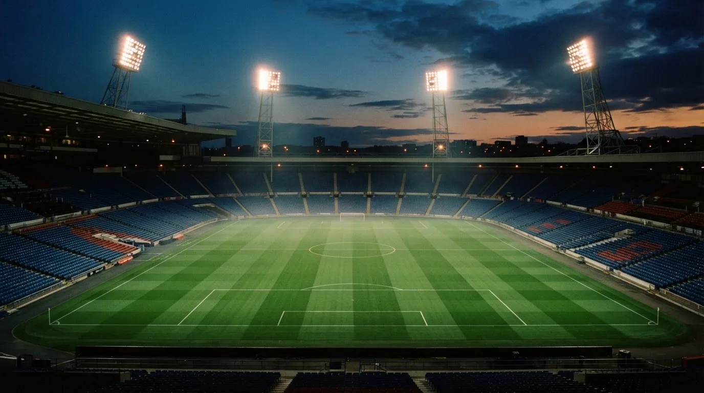 Een leeg voetbalstadion met lichtmasten bij schemering