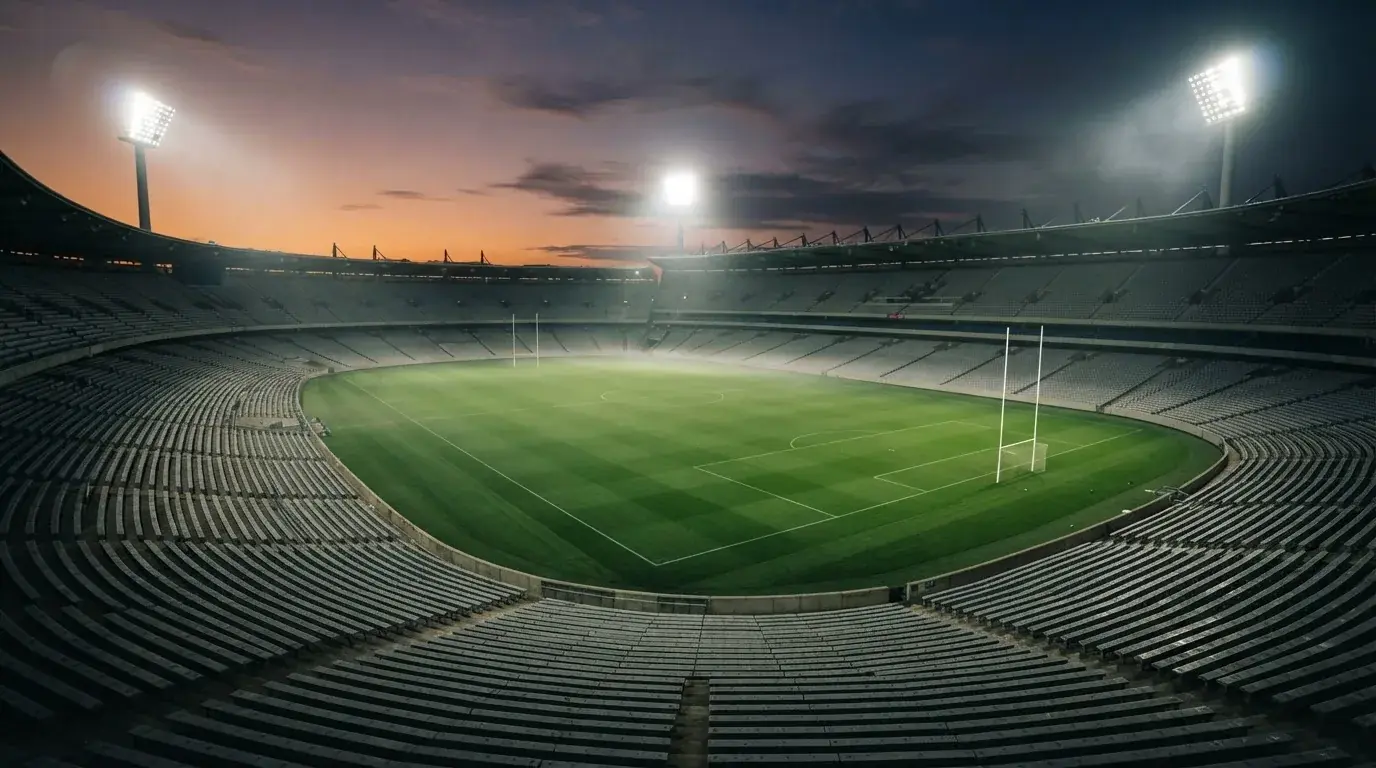 Een leeg voetbalstadion met lichtmasten bij schemering