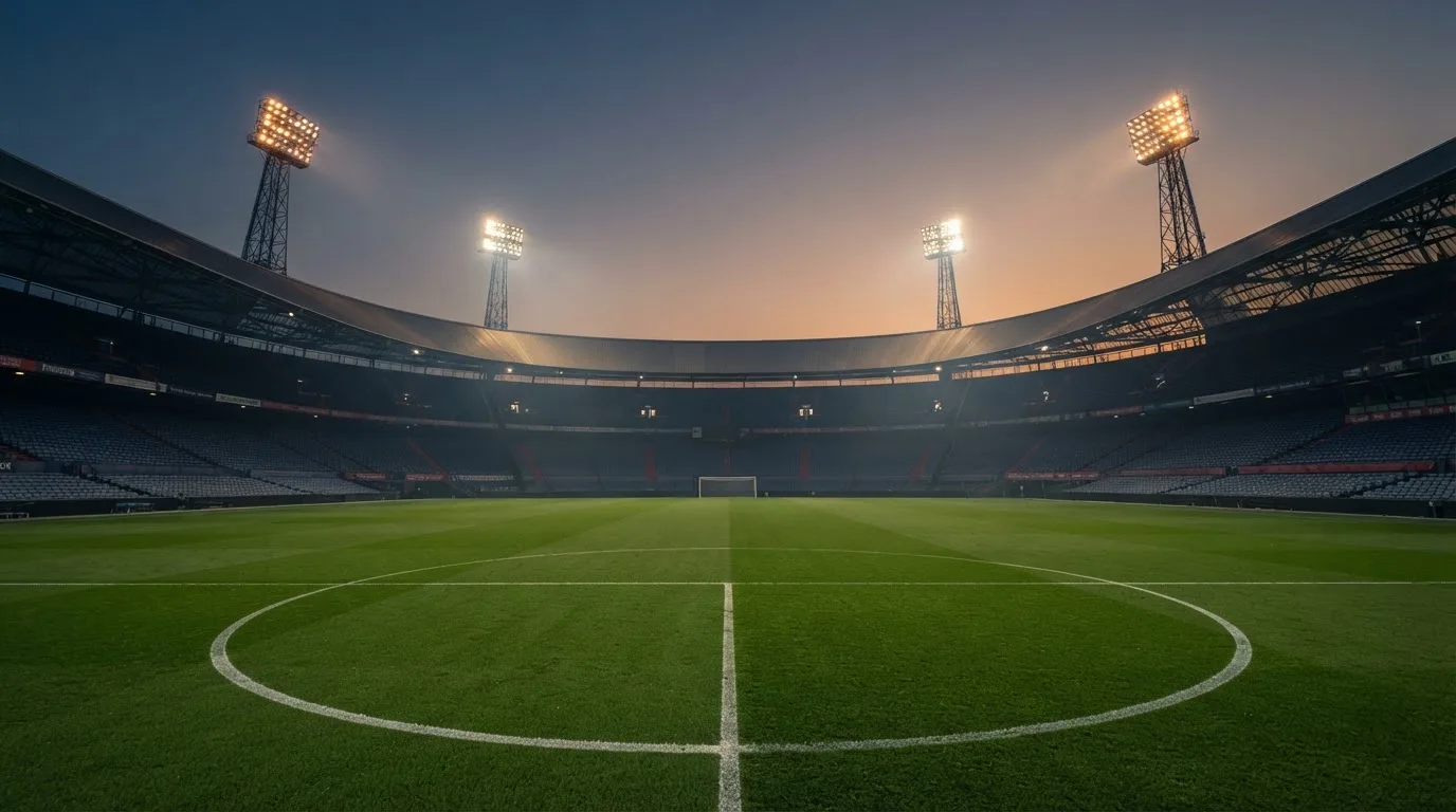 Een leeg voetbalstadion met lichtmasten bij schemering