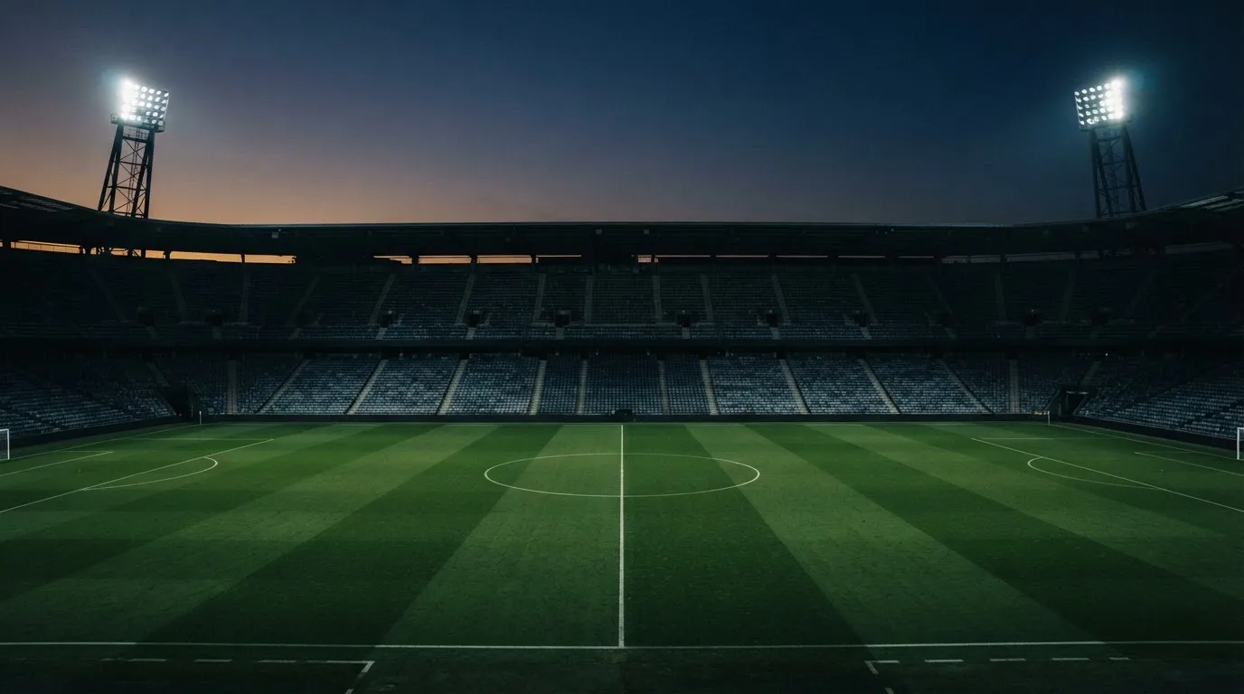 Een leeg voetbalstadion met lichtmasten bij schemering