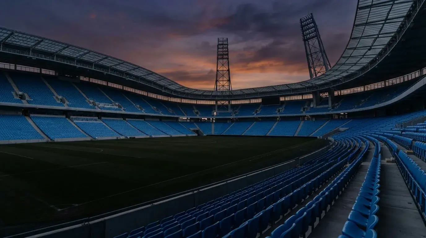 Een leeg voetbalstadion met lichtmasten bij schemering