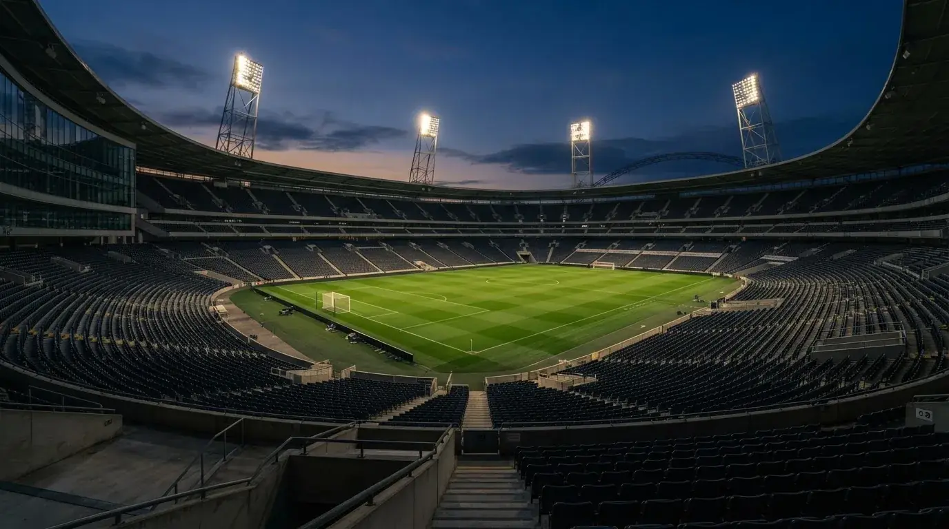 Een leeg voetbalstadion met lichtmasten bij schemering
