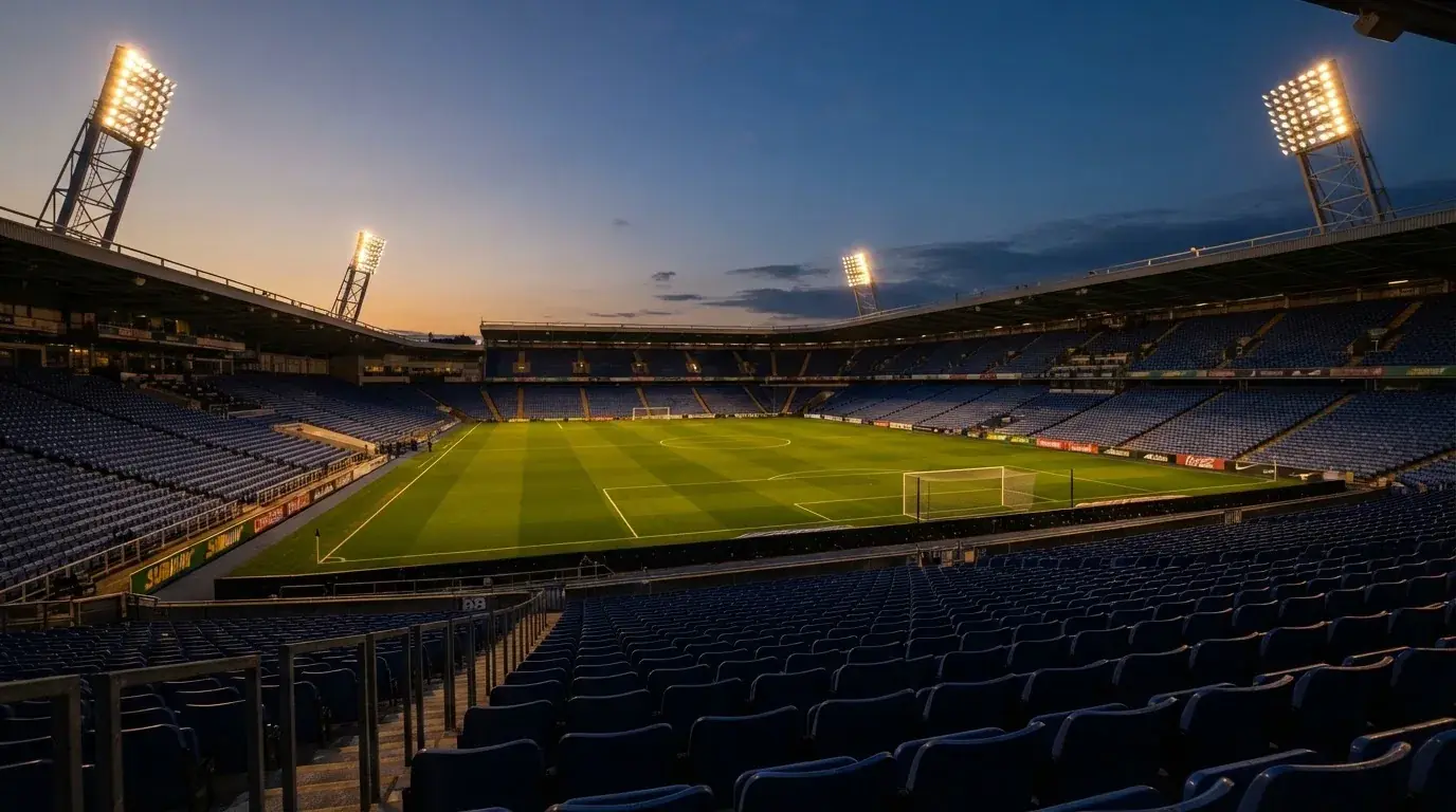 Een leeg voetbalstadion met lichtmasten bij schemering