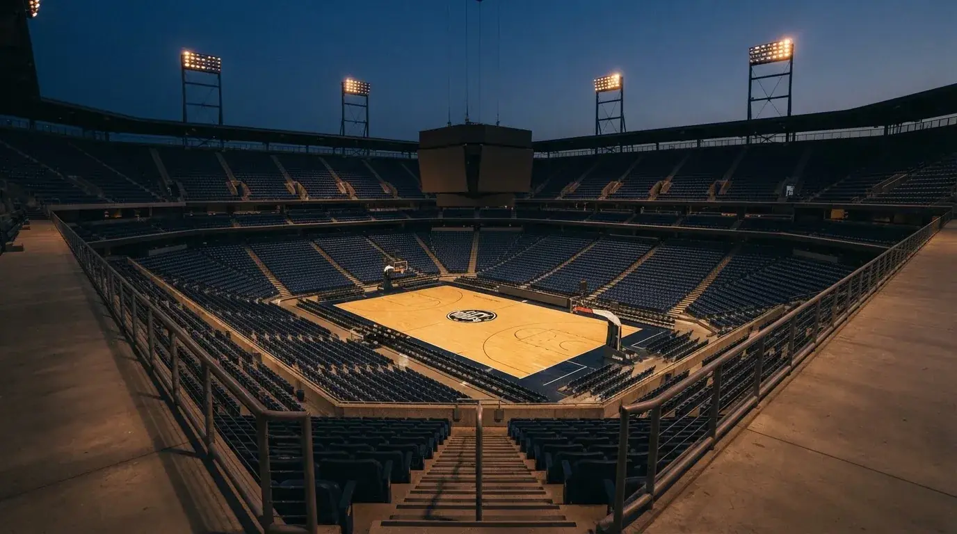 Een leeg voetbalstadion met lichtmasten bij schemering