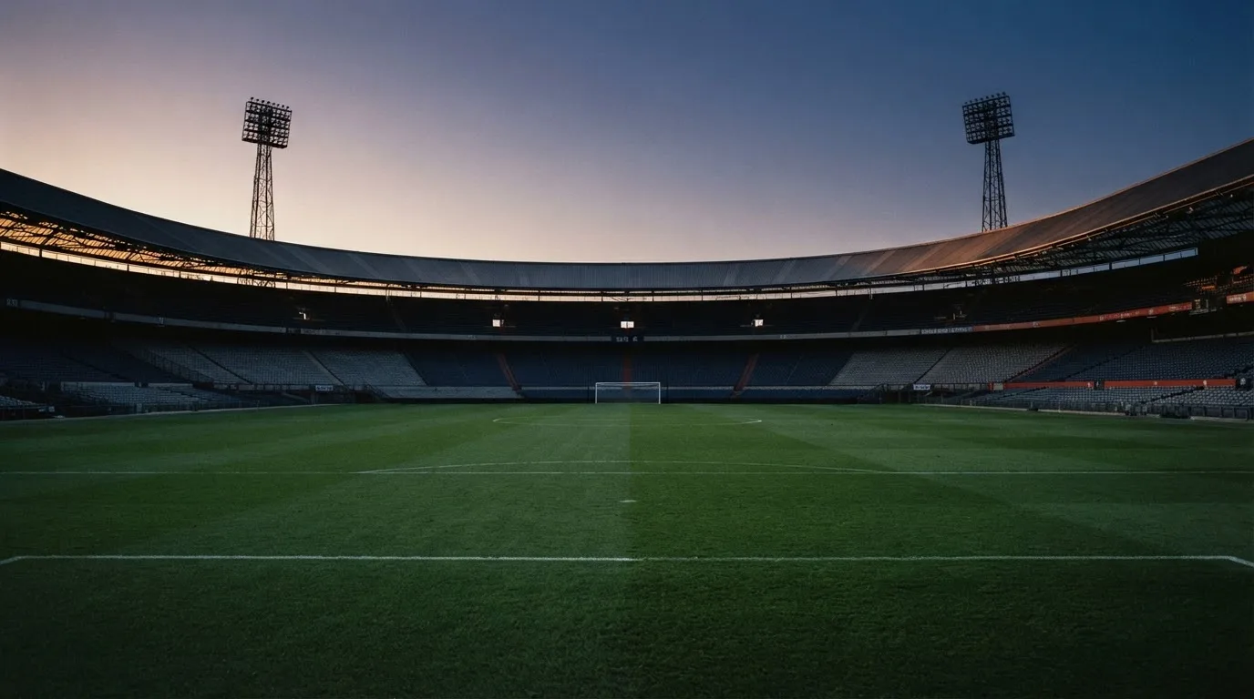 Een leeg voetbalstadion met lichtmasten bij schemering