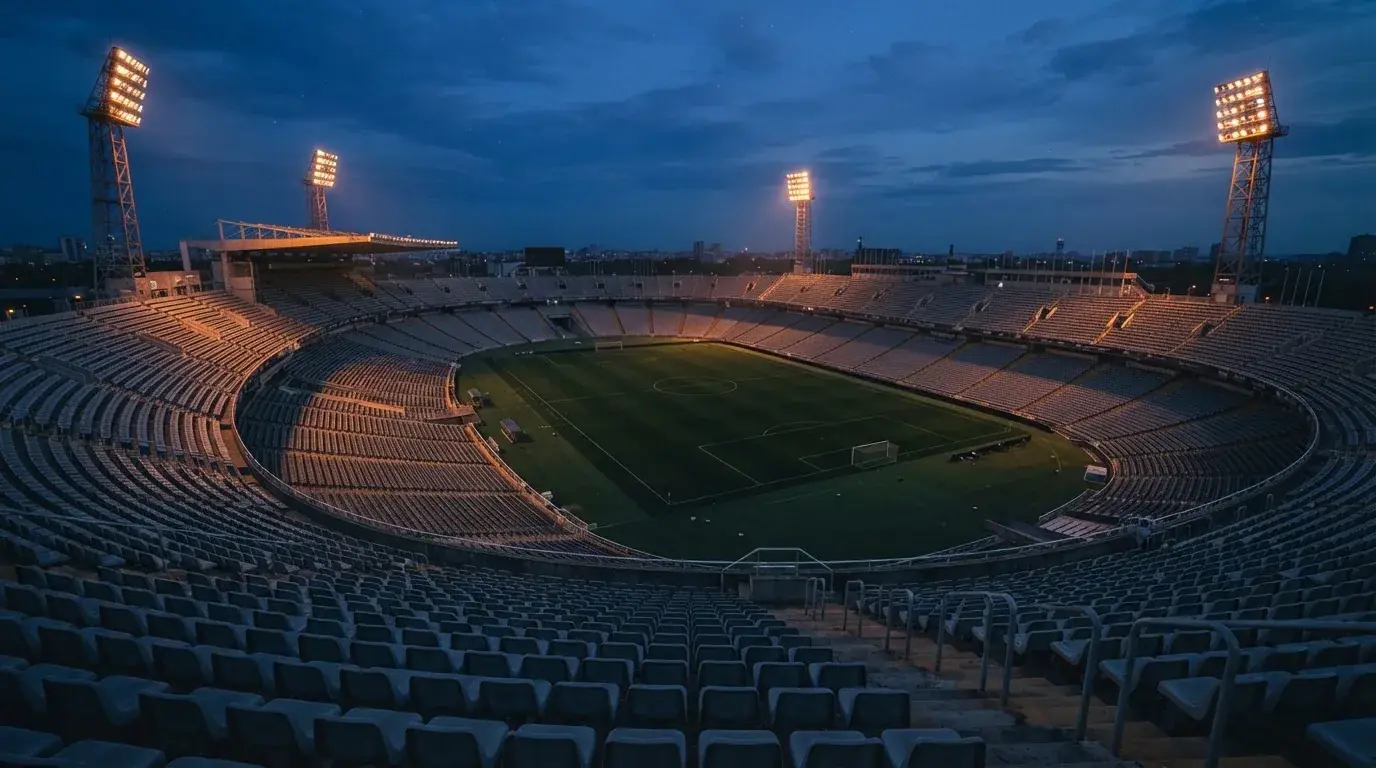Een leeg voetbalstadion met lichtmasten bij schemering