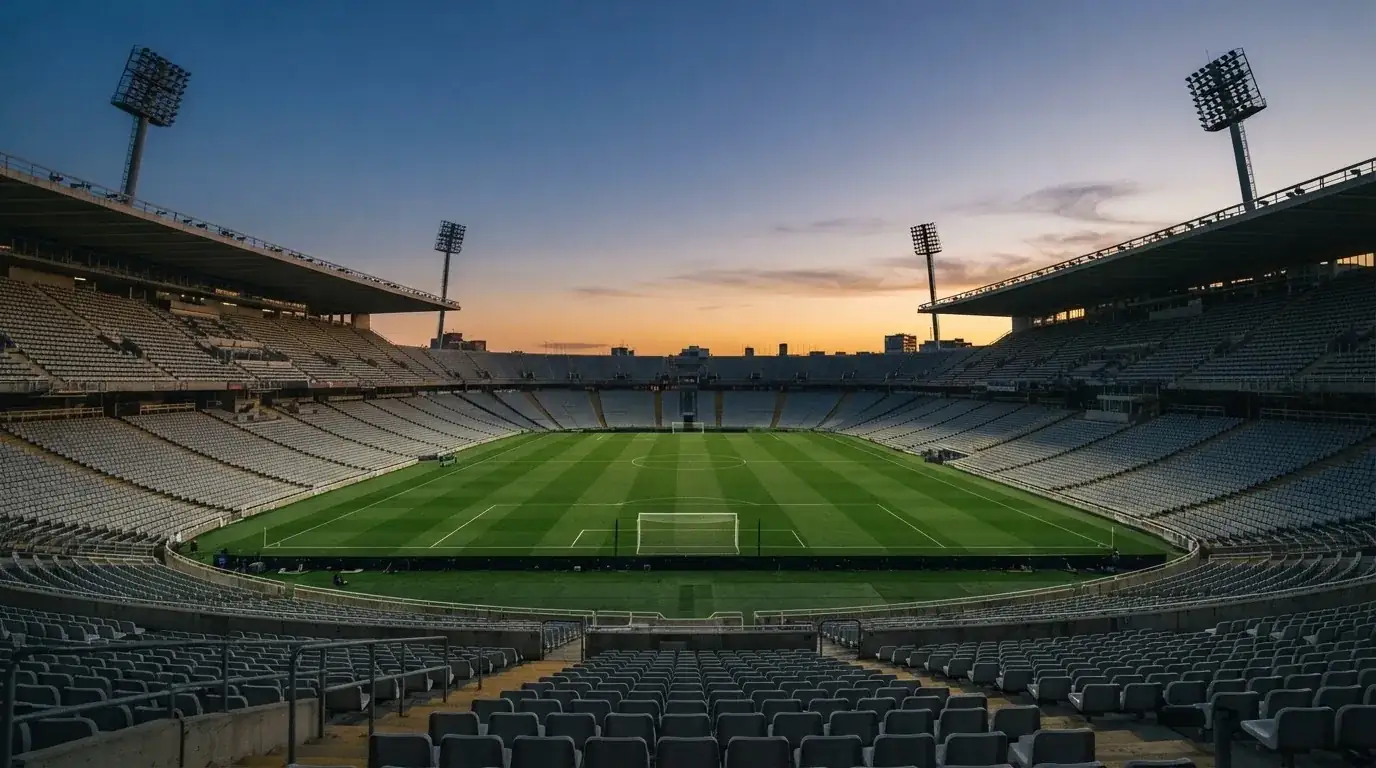 Een leeg voetbalstadion met lichtmasten bij schemering